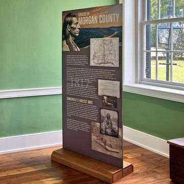Cherry sign base with an 80-inch Morgan County history panel in a restored courthouse room