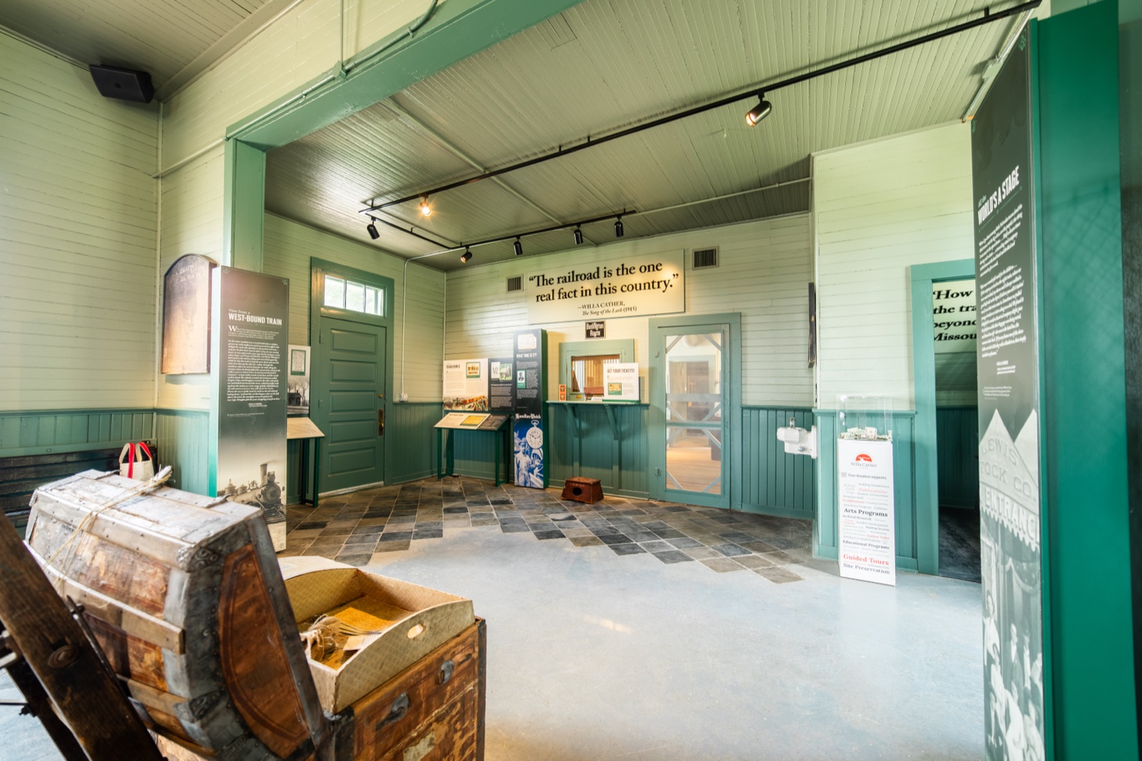 Restored waiting room of the Burlington Depot with green woodwork, exhibit panels, and an antique trunk