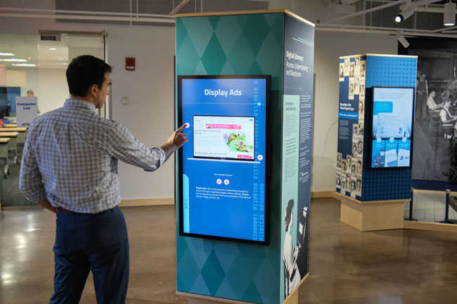 Graham Unruh interacting with the digital touchscreens on the exhibit columns.