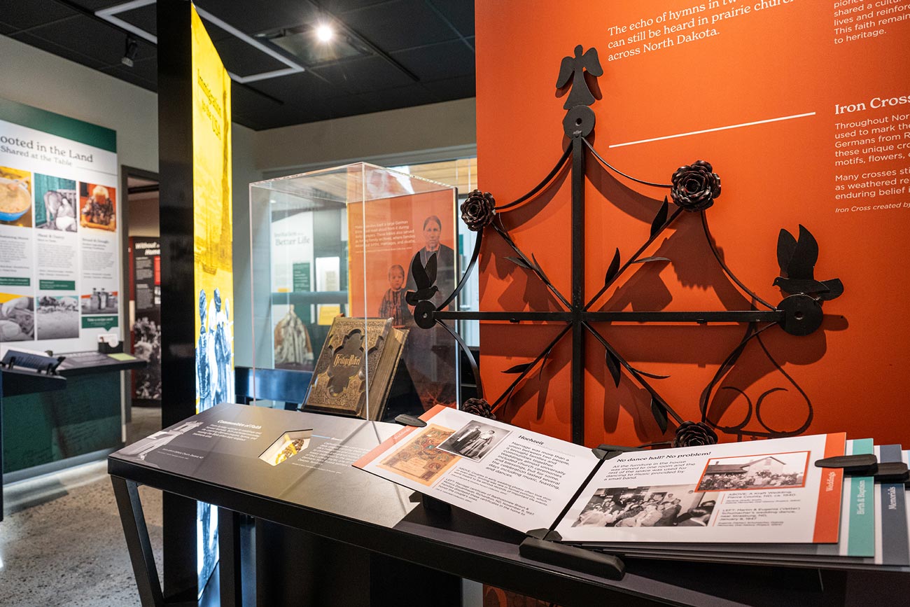 The Iron Crosses display — a wrought-iron grave cross against a deep orange wall